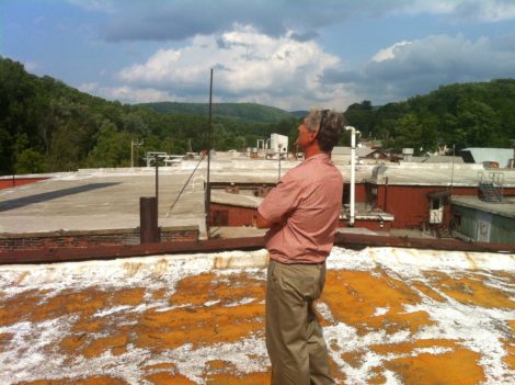 Architect Doug Brown on the roof of the Smith Mill complex looking toward Lenoxdale. The roof is visibly deteriorating and the footing is a bit tricky. Photo: Daniel Bellow