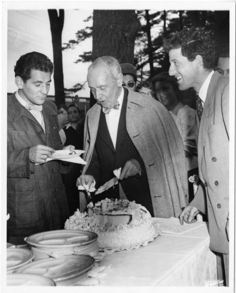 Leonard Bernstein and Lukas Foss stand on either side of Serge Koussevitzky as he cuts his birthday cake at Tanglewood ca 1946. Photo: Courtesy of Boston Symphony Orchestra