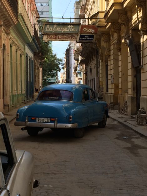 A narrow street in Havana, with cars dating from the 1950s (like the blue Chevrolet).