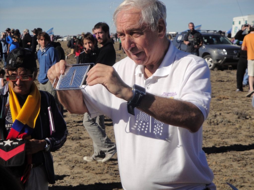 Professor Pasachoff uses a cheese grater to make dozens of pinhole images at the same time. Man on the left wears eclipse-filtering glasses. Image courtesy of Jay M. Pasachoff, published with permission