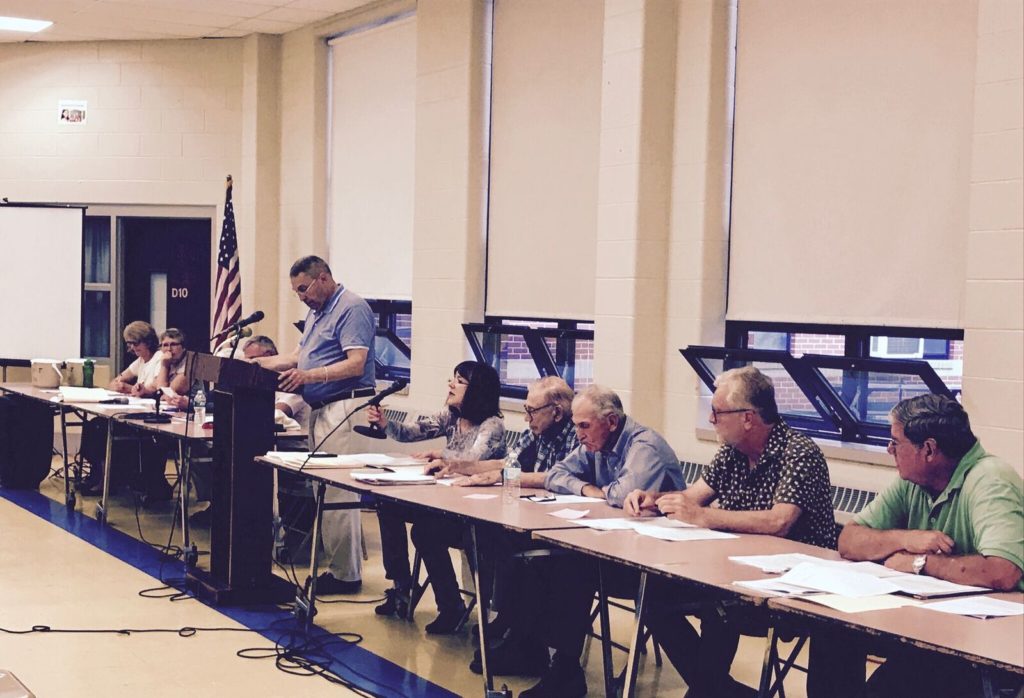 Moderator Steve Cohen, with town officials on his left and the town finance committee on his right, opens up the meeting to a vote. Photo: Victor Feldman