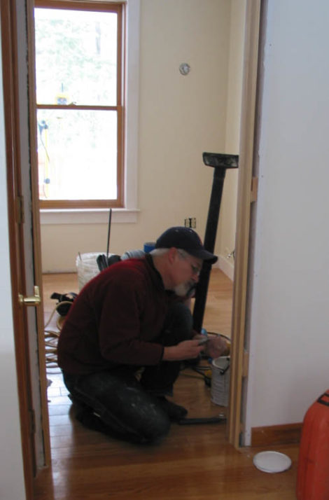 Contractor Thom Whaley is shown finishing new trim in the space that became the office. Seen from the dining room, the new oak flooring matched the original. - Photo Credit: Erica Fay