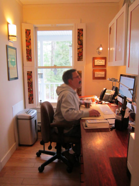 The completed galley-style office from the same view. Custom cabinets were installed above the desk top. The hall out to the entry with the powder room and coat closet is behind the seated gentleman. - Photo Credit: Erica Fay